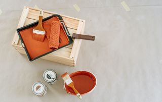 pot de peinture orange avec pinceaux et rouleau